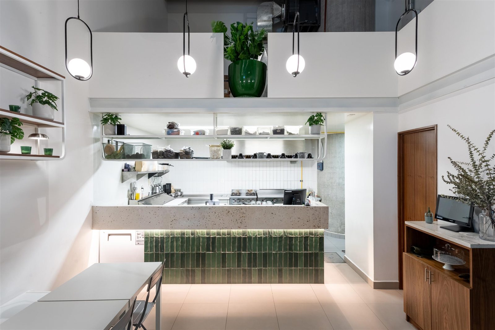 Zampar: cocina abierta con azulejo verde, barra de concreto y luminarias colgantes