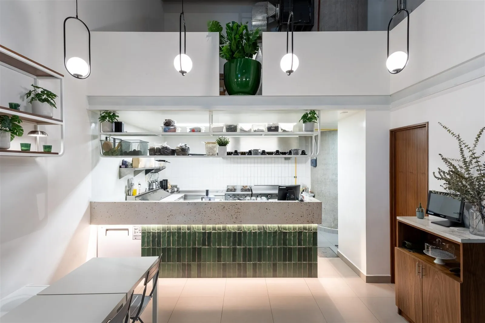 Zampar: cocina abierta con azulejo verde, barra de concreto y luminarias colgantes
